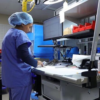 A hospital worker working in front of a computer dressed in scrubs