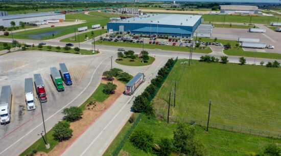 Drone shot of a building and a parking lot filled with semis