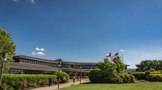 Building in Temple with people walking out. Green grass and blue skies can be seen.