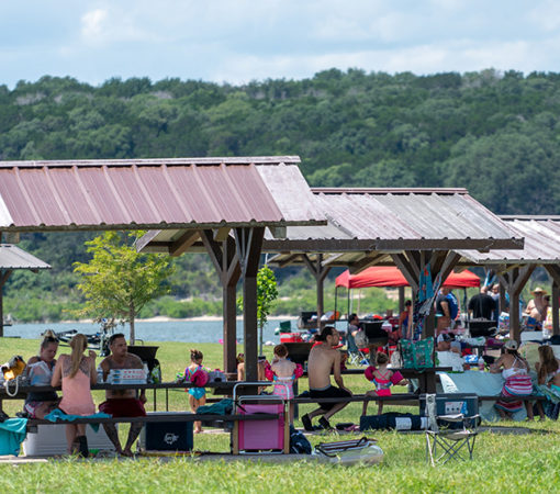 Families sit outside and enjoy the summer weather at picnic tables next to Lake Belton in Temple, TX
